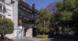 Texto alternativo (ALT) Fachada contemporánea de departamentos de gran formato en CDMX, ubicada en una calle arbolada de una zona residencial premium.
